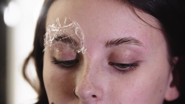 Eyebrow lamination - an eyebrow specialist combs the eyebrow hairs up with a remedy on them
