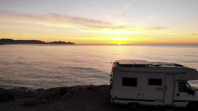 Aerial view. Flying above camper rv camping on coast sea shore at sunrise. Adventure, travel with mobile home.