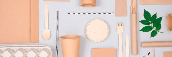Banner. Flat lay with eco-friendly tableware and sustainable packaging. Kraft paper food packaging on gray background. Street food paper packaging, recyclable paperware, zero waste packaging concept