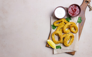 Fried squid rings with two sauces, lemon and herbs. Fast food. Appetizer.