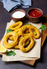 Fried squid rings with two sauces, lemon and herbs. Fast food. Appetizer.