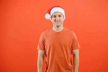 Portrait of happy and excited man in santa hat, rejoicing and winning something, celebrating new year, standing over red background