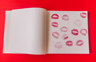  Lots of lip prints on white paper on a red background with space to insert. High quality photo