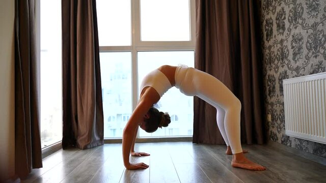 Athletic woman in sportswear shakes her abdominals. Athletic woman doing abs exercises on the floor on a mat at home, side view. Sports and fitness. The concept of training, training and wellness