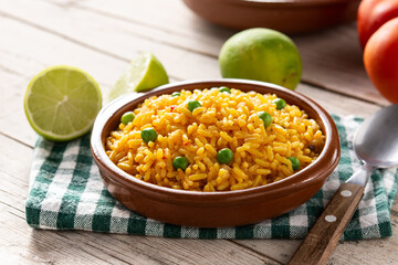 Traditional Mexican rice served with green peas in bowl on wooden table