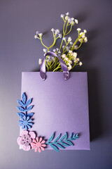 Purple paper bag with handmade flowers on a purple background