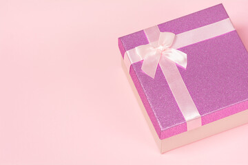 Violet gift box on a pink background. Birthday, mother's or valentine's day gift. Holiday and generosity concept