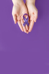 International Epilepsy Day. Adult hands holding purple ribbon on purple background. Alzheimer's disease, Pancreatic cancer, Hodgkin's Lymphoma awareness
