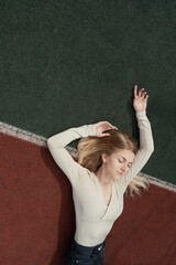 Young blonde female lying on a backetball sport field wih her eyes closed, selective focus