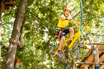 Naklejka na ściany i meble Adorable little girl enjoying her time in climbing adventure park on warm and sunny summer day
