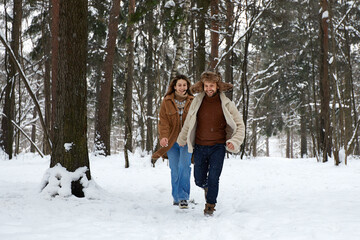Fototapeta na wymiar People, season, love and leisure concept - happy couple hugging and laughing outdoors in winter. Couple embracing and having fun in snowy winter park