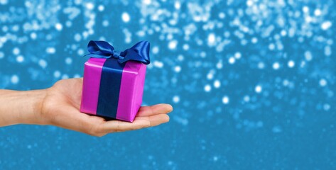 Hands holds Christmas gift on bokeh background