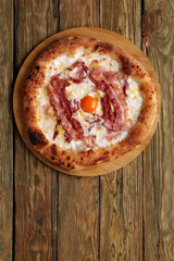 Carbonara pizza with bacon and egg on wooden background