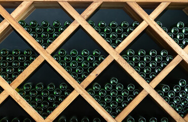 Resting wine bottles stacked on wooden racks in cellar