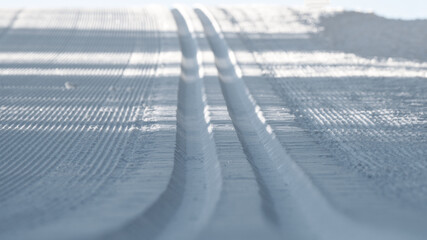 a freshly prepared nordic skiing slope on the mountains at a sunny winter day in the morning