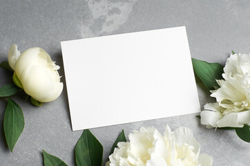 Greeting or invitation card mockup with copy space and white peony flowers on grey