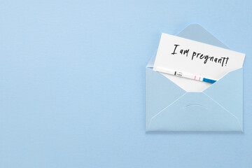 positive pregnancy test in blue envelope on blue background, postcard with inscription i am pregnant, pregnancy concept.