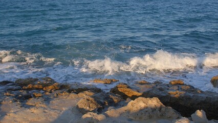 Sea water hits the stone shore. Small waves are breaking. Water tide to the coastline. Natural natural phenomenon.