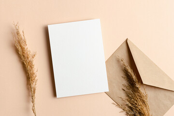 Invitation card mockup with envelope and dry plant decorations on beige background
