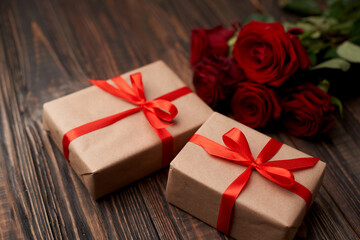 gift boxes and a bouquet of roses on a wooden countertop.