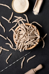 Whole grain wheat raw apulian pasta called Pizzarieddi or maccaruni in a bowl on black table. Fresh...