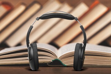 Obraz na płótnie Canvas Headphones lying next to old books on the desk. Audiobook Concept