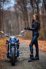 Fototapeta na wymiar a beautiful long-haired woman with a motorcycle in the autumn forest