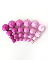 Purple and pink yarn and thread on a white background.