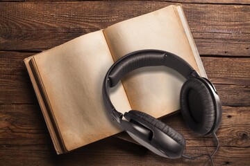 Headphones lying next to old books on the desk. Audiobook Concept