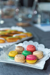 several colorful macarons in a plate with an openwork napkin