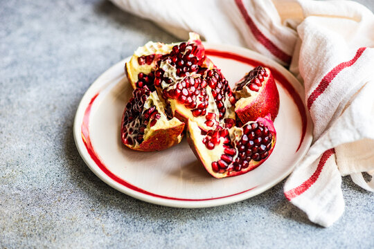 Overhead view of ripe organic pomegranate segments on a plate next to a tea towel