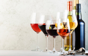 Red, rose and white wine glasses set on gray table background. Wine tasting. Hard light and harsh shadows