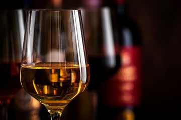 Red, white and rose wine in glasses on wooden background and collection of wine bottles, copy space