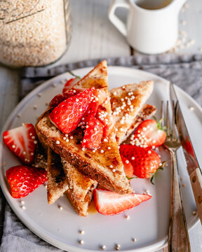 Plate of French toast with strawberries, puffed quinoa and syrup