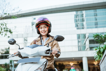 Asian woman riding a motorcycle wearing a helmet