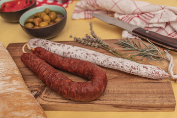 Fuets Catalan dry sausages. Set of spanish sausages and dry cured meat chistorra, chorizo, salchichon, fuet, olives, rosemary, chili peppers on a wooden background. top view.