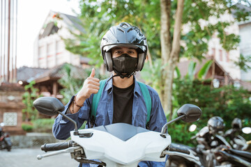 Young man wearing helmet and mask with thumbs up
