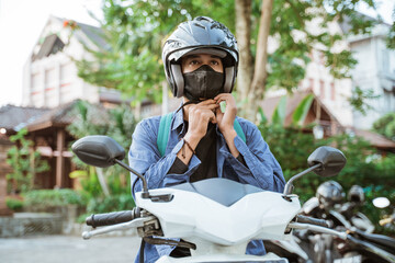 Man getting ready to wear helmet and mask on motorbike