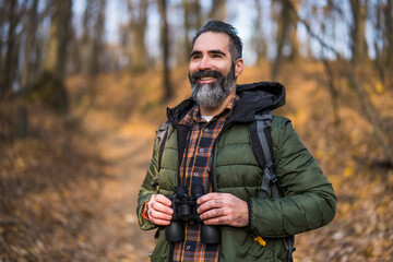 Obraz premium Image of man hiking and using binoculars. 