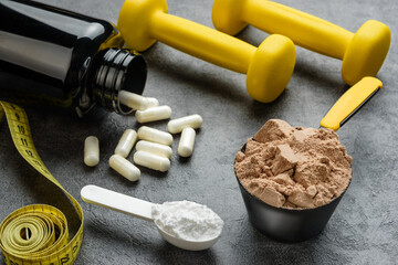 measuring spoons with chocolate protein and creatine, amino acid capsules, dumbbells and measuring...