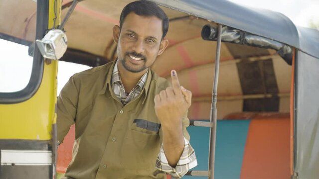 Smiling auto driver showing Ink marked finger after voting in election by looking at camera - concept of democracy, Indian election and responsibility