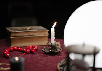 Close-up dark photo of candles, lamps and beads on a fortune teller's table. Interior concept