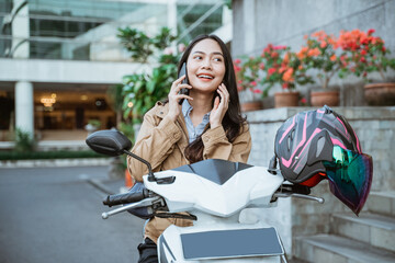 Beautiful woman making a call on a motorbike
