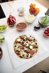 Woman adding healthy ingredients to pizza. Home made concept. top view.