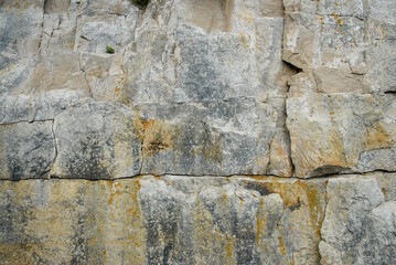 Weathered and textured rocks on a cliff with cracks and an abstract design