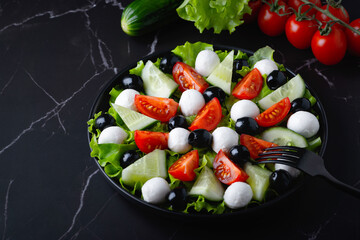 Fresh salad with cucumbers, tomatoes, black olives and feta or mozzarella cheese, with olive oil and celery