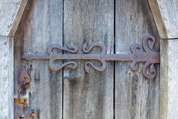 Forged antique hinge on a fragment of an old wooden door.