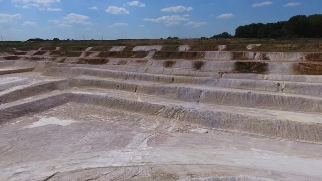 Sloping stairs created on the ground after the process of mining kaolin. Drone footage. Blue sky background.