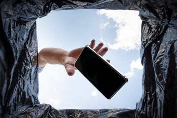 man throws a non-working smartphone into a trash can. Bottom view from the trash can. The problem...