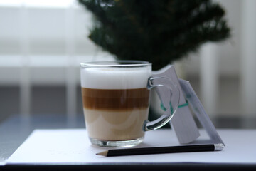 Aroma three-layer cappuccino with foam in a transparent cup in the office.